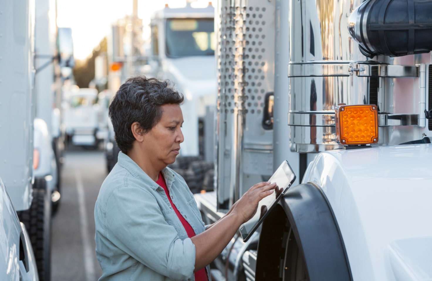 Hispanic American female truck driver going over dispatch list on her tablet using an app designed and developer by Cuttlesoft.