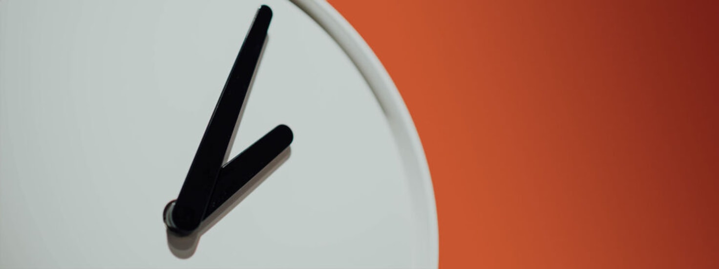 Analog clock on orange wall symbolizing Cuttlesoft's precision in tracking project performance metrics