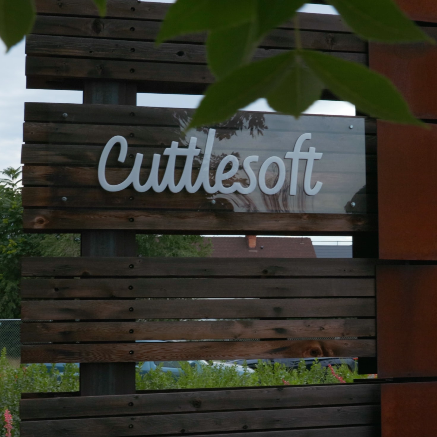 The Cuttlesoft company sign mounted on natural wood slats reflects our approach to full-stack development - combining modern technology with sustainable, grounded practices. Located at our Denver headquarters, this exterior signage represents where our distributed team of full-stack developers converges, building web applications with Python, React, and Ruby technologies. The organic materials and surrounding greenery mirror our development philosophy - creating well-crafted, lasting solutions that grow with our clients' needs. This professional yet approachable branding shows how we blend technical excellence with human-centered development practices.