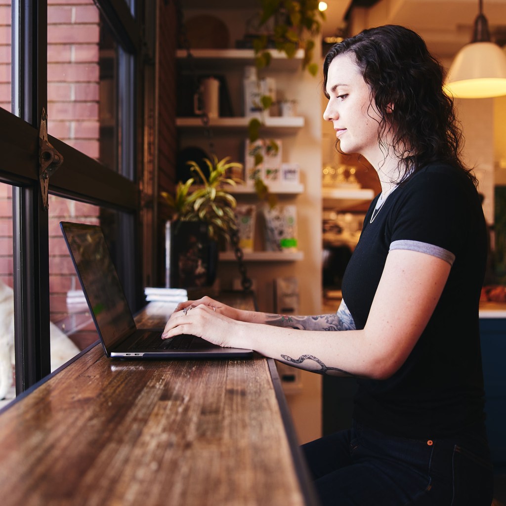An AI specialist at Cuttlesoft works on machine learning implementation at a standing desk near natural light, reflecting our flexible approach to complex AI development. Her focused attention represents our detailed work in NLP and computer vision projects, where careful model development and training are essential. The modern, comfortable workspace with plants and natural elements shows how Cuttlesoft creates an environment conducive to solving complex AI challenges, from fine-tuning large language models to developing custom computer vision solutions. This setting demonstrates our commitment to combining technical excellence with human-centered development practices in AI consulting and implementation.