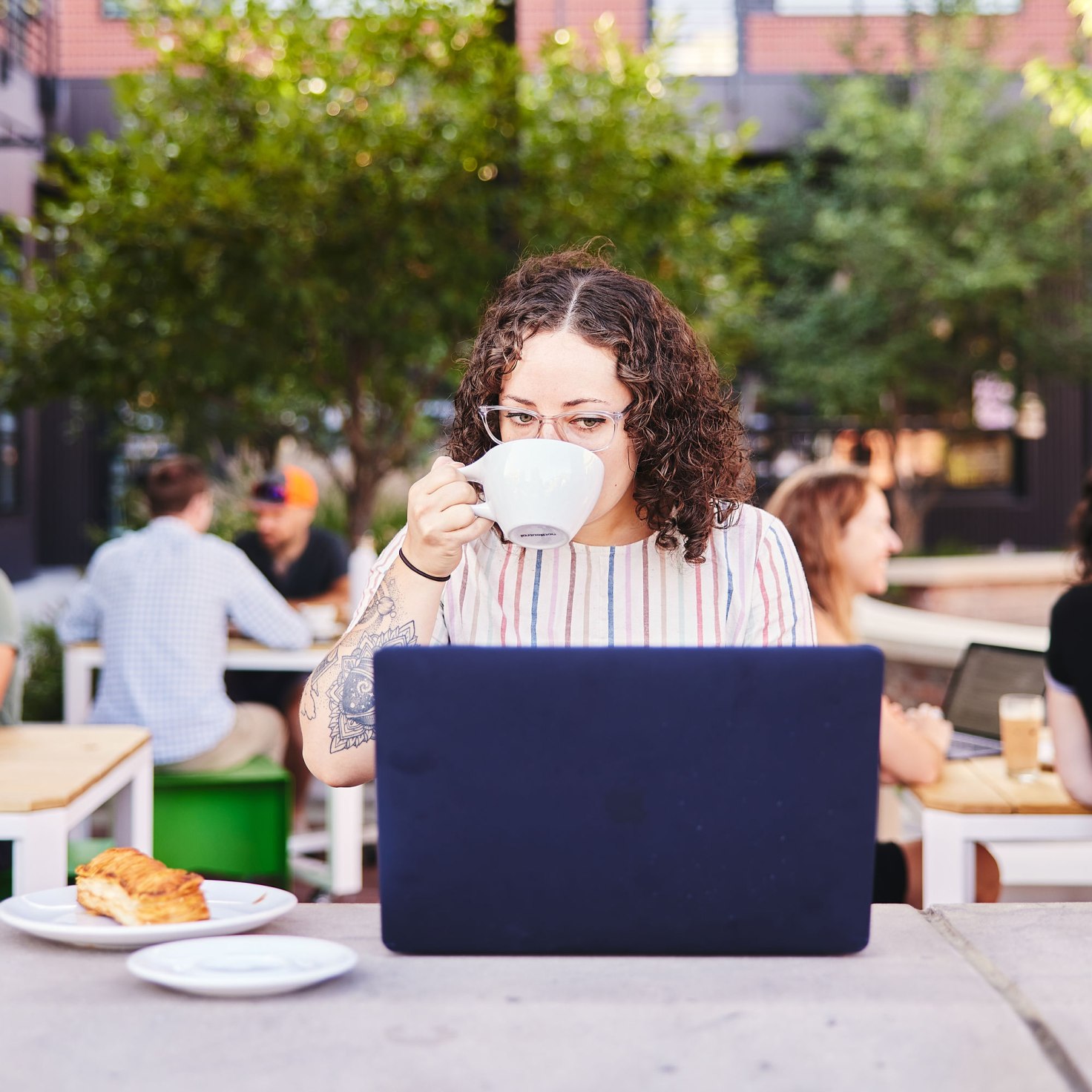 Marisa takes a sip of coffee while she waits for code to finish testing in AWS CodePipeline.