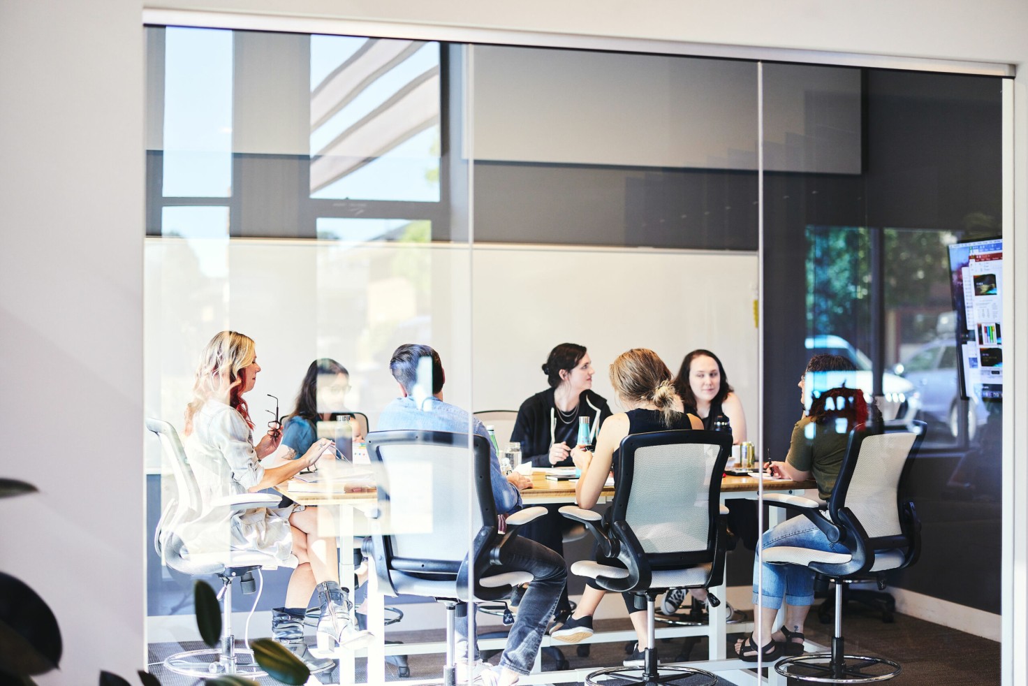 Team meeting through glass walls - Cuttlesoft employees collaborating in their modern Denver office space.